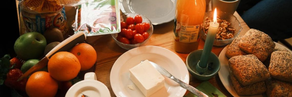 A cozy breakfast spread featuring fresh fruits, bread, and juice, surrounded by warm candlelight.
